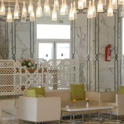 Salon de réception luxueux de l'hôtel Helios Beach à Djerba avec luminaires modernes et mobilier design.