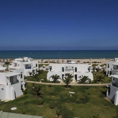 Panorama des bungalows blancs de l'hôtel Helios Beach face à la mer azur de l'île de Djerba.