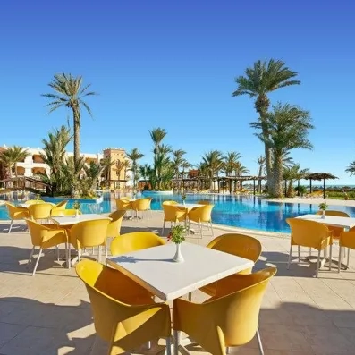 Terrasse ensoleillée avec tables et chaises jaunes face à la piscine de l'hôtel Safira Palms à Djerba.