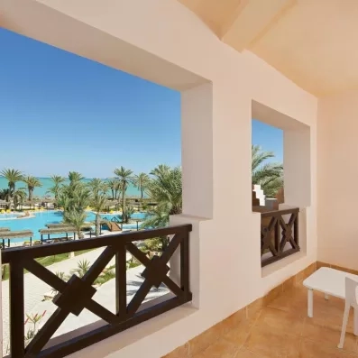 Vue panoramique depuis le balcon d'une chambre sur la piscine, les jardins et la plage de Djerba.