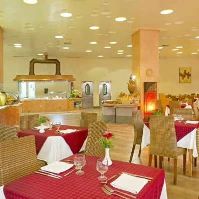 Restaurant buffet spacieux avec tables dressées et chaises en osier à l'hôtel Safira Palms à Djerba.