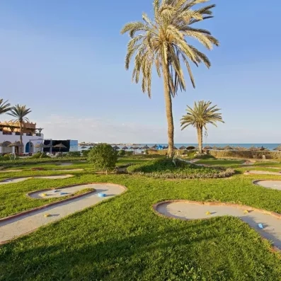 Parcours de mini-golf verdoyant avec palmiers en bord de mer à l'hôtel Safira Palms Djerba.