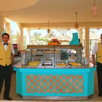 Serveurs en tenue devant un buffet de fruits frais au restaurant de l'hôtel Zephir à Djerba.
