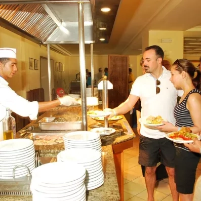 Chef cuisinier servant des clients au buffet chaud lors d'un séjour tout compris à Djerba.