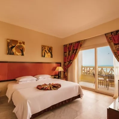 grand lit chambre double avec porte fenêtre menant vers le balcon, vue sur mer