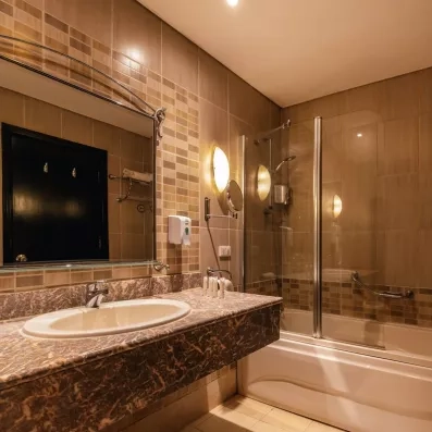 salle de bain avec baignoire vitré, grand vasque en marbre et lavabo intégré, miroir accroché au mur