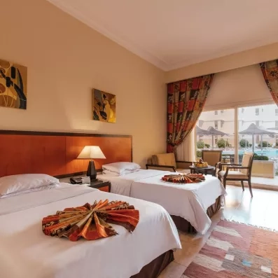 chambre lits séparés avec porte fenêtre menant vers la terrasse, vue sur jardins et piscine