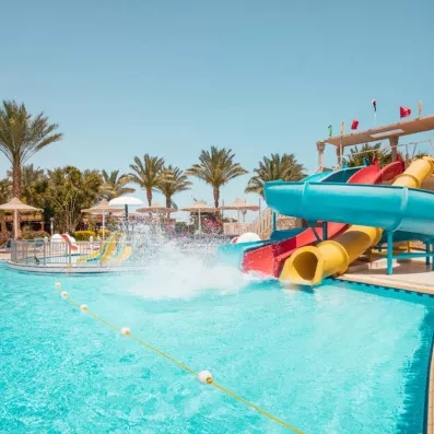 Parc aquatique avec toboggans colorés et palmiers pour des vacances en famille à l'hôtel AMC Hurghada.
