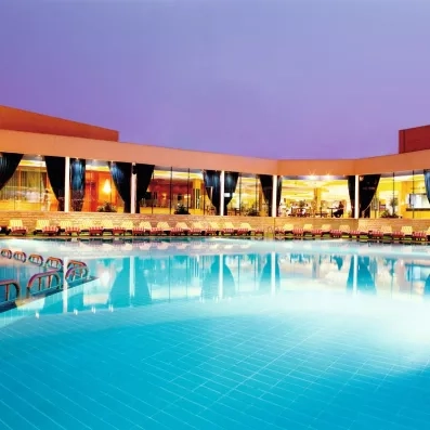 Piscine extérieure de l'hôtel Cairo Pyramids 5 éclairée le soir, cadre relaxant pour votre voyage.