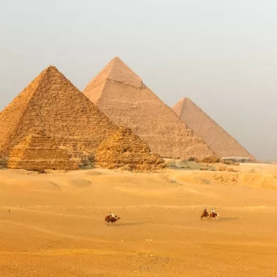 Grandes Pyramides de Gizeh au Caire et caravane de chameaux, merveille du monde et symbole du tourisme.