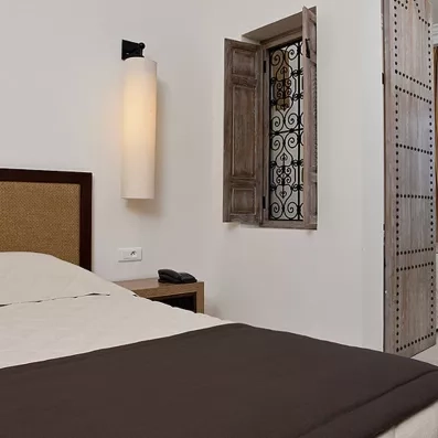 Détail d'une chambre avec fenêtre traditionnelle en fer forgé et décoration authentique pour un voyage à Djerba.