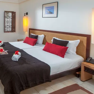 Literie confortable et touches de design tunisien dans une chambre élégante de l'hôtel Sentido Djerba Beach.