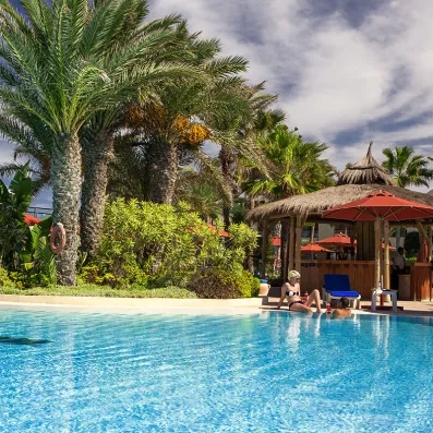 Bar de piscine au toit de chaume et voyageurs profitant du soleil tunisien à Djerba.