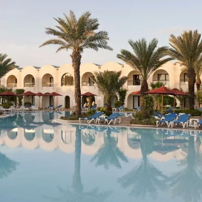 Reflets des palmiers et du bâtiment sur la piscine calme au coucher du soleil à Djerba.