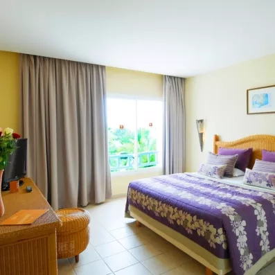 Chambre d'hôtel lumineuse au Djerba Resort offrant une vue sur les jardins tropicaux depuis la fenêtre.