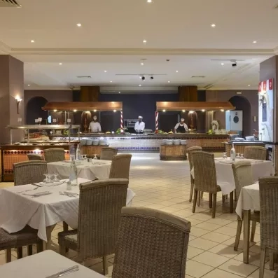 Salle de restauration élégante et buffet avec chefs cuisiniers en action pour des vacances gourmandes en Tunisie.