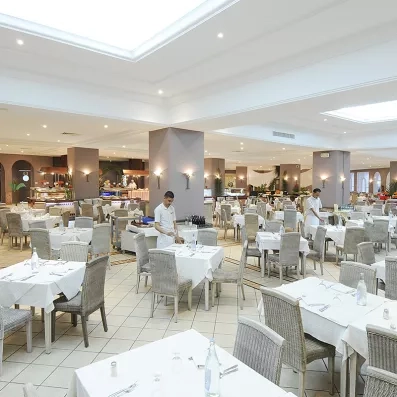 Grand restaurant buffet lumineux du Djerba Resort avec serveurs préparant les tables pour un séjour en Tunisie.