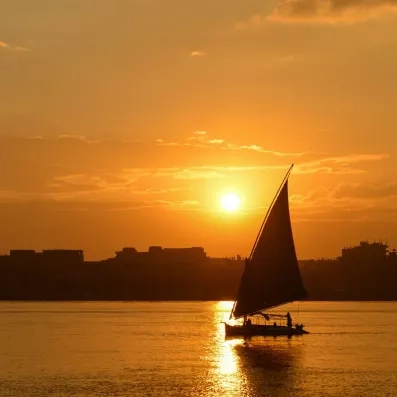 Silhouette d'une voile de felouque sur le Nil lors d'un coucher de soleil romantique à Louxor.