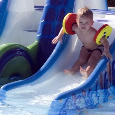 Jeune enfant glissant sur un petit toboggan de piscine au Jaz Aquamarine Hurghada, séjour familial sécurisé.