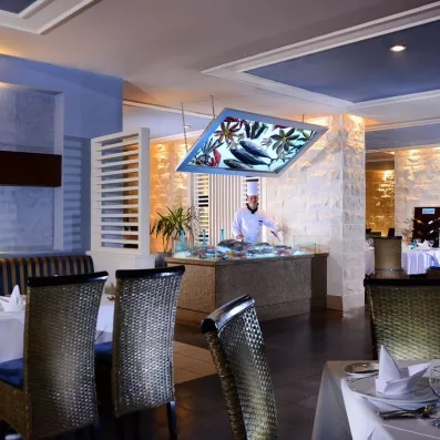 Buffet de poissons frais au restaurant Jaz Aquamarine Hurghada, chef cuisinier et tables dressées, séjour luxe Égypte.