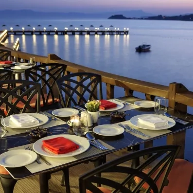 Un dîner raffiné en bord de mer sur une terrasse en bois, avec des tables dressées.