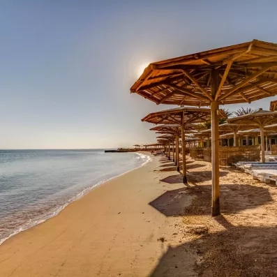 transats, parasols en bois au bord de la mer avec sable fin, soleil