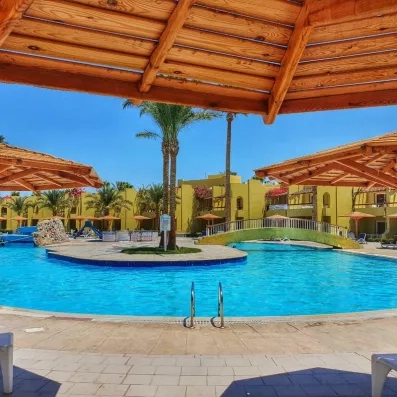 piscine avec pont qui traverse au milieu, parasols en bois, soleil, palmiers