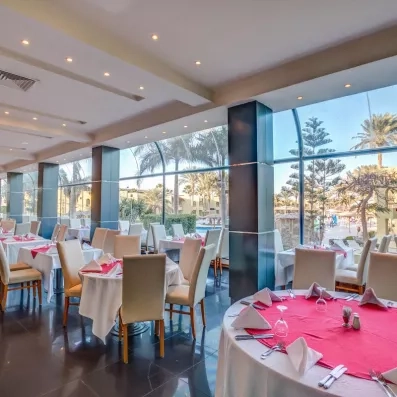 Grande salle de restaurant de l'hôtel, vitre donnant sur le jardin extérieur, tables dressées 