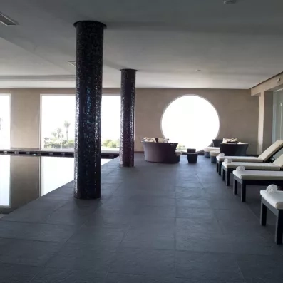 Espace de relaxation design avec transats et colonnes mosaïques face à la piscine au Royal Thalassa Monastir.