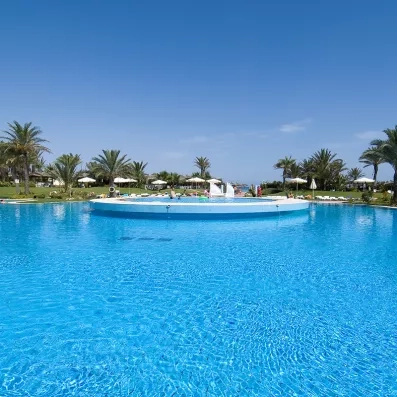 Piscine lagon aux eaux bleues cristallines entourée de palmiers sous un ciel dégagé à Monastir.