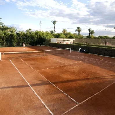 Court de tennis en terre battue entouré de palmiers au complexe touristique Sahara Beach Monastir.
