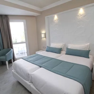 Chambre lumineuse avec tête de lit sculptée et accents bleus pour un séjour détente au Sahara Beach.