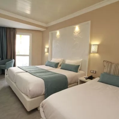 Suite familiale spacieuse avec trois lits confortables et design contemporain à l'hôtel Sahara Beach à Monastir.