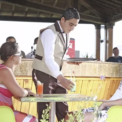 Serveur proposant des cocktails rafraîchissants en terrasse pour des vacances détente à Monastir.