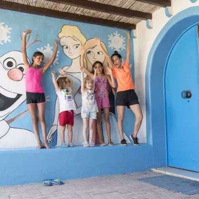 Enfants posant devant une fresque murale colorée lors d'une animation au Mondi Club Shems Monastir.