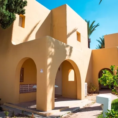 Bungalows à l'architecture saharienne jaune sous un ciel bleu au Mondi Club Shems à Monastir.