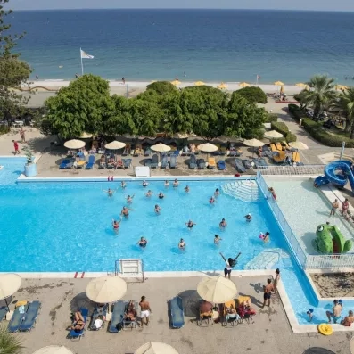 groupe de touristes dans la piscine extérieur avec des transats, parasoles et des végétations sur la plage