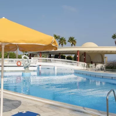 piscine avec un pont vers le bar de l'hôtel  parasol jaune