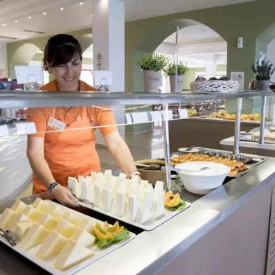 serveuse posant sur le buffet un plateau de fromages au restaurant de l'hôtel