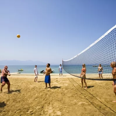 Des joueurs s'affrontent lors d'une partie de volley-ball sur une plage en bord de mer.