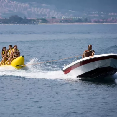 Un bateau à moteur tracte une bouée dans la mer, pour une activité aquatique.