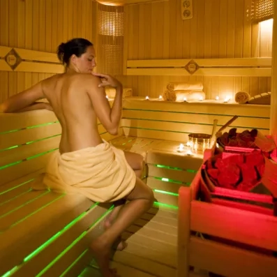 Une femme se relaxe dans un sauna en bois agrémenté de bougies.
