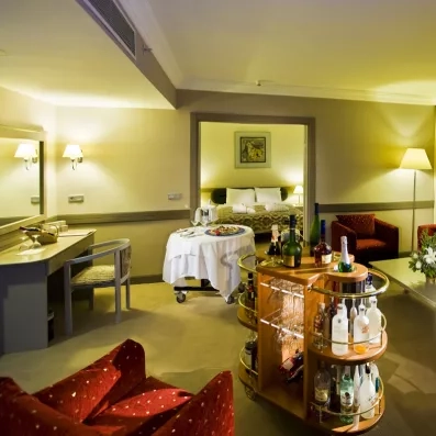 Une chambre avec un coin salon, qui propose des fauteuils et un bar mobile.