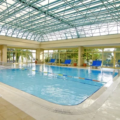 Une grande piscine intérieure est baignée de lumière naturelle grâce à une immense verrière.