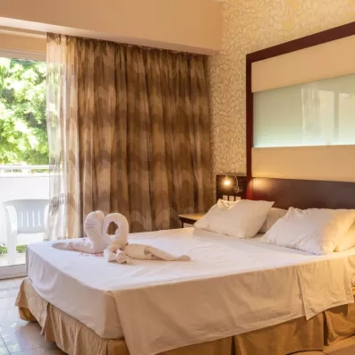 chambre avec un lit double standard en blanc et une porte fenêtre qui mène vers la terrasse 