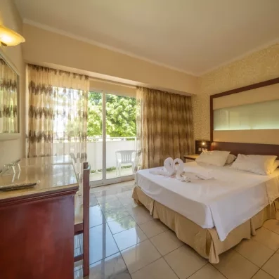 chambre avec un lit double standard en blanc et une porte fenêtre qui mène vers la terrasse 