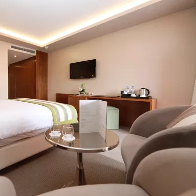 Chambre avecgrand lit de deux places, TV accroché et deux chaises avec table d'appoint