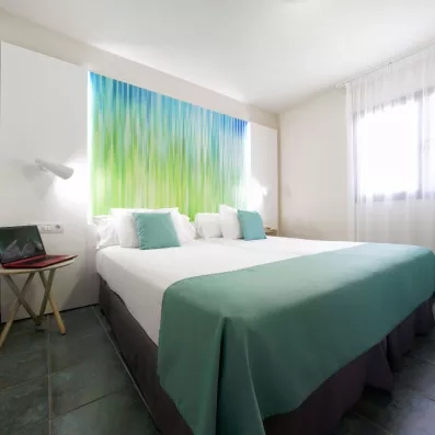 Une chambre avec un lit double lumineuse avec une décoration murale.