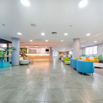 Un vaste lobby lumineux et épuré avec un sol brillant, doté de plusieurs fauteuils.