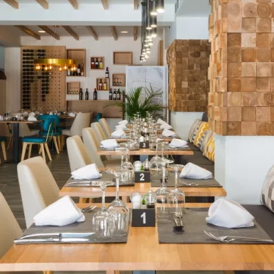 Une table de restaurant préparée avec des serviettes blanches, des verres à vin et des couverts.